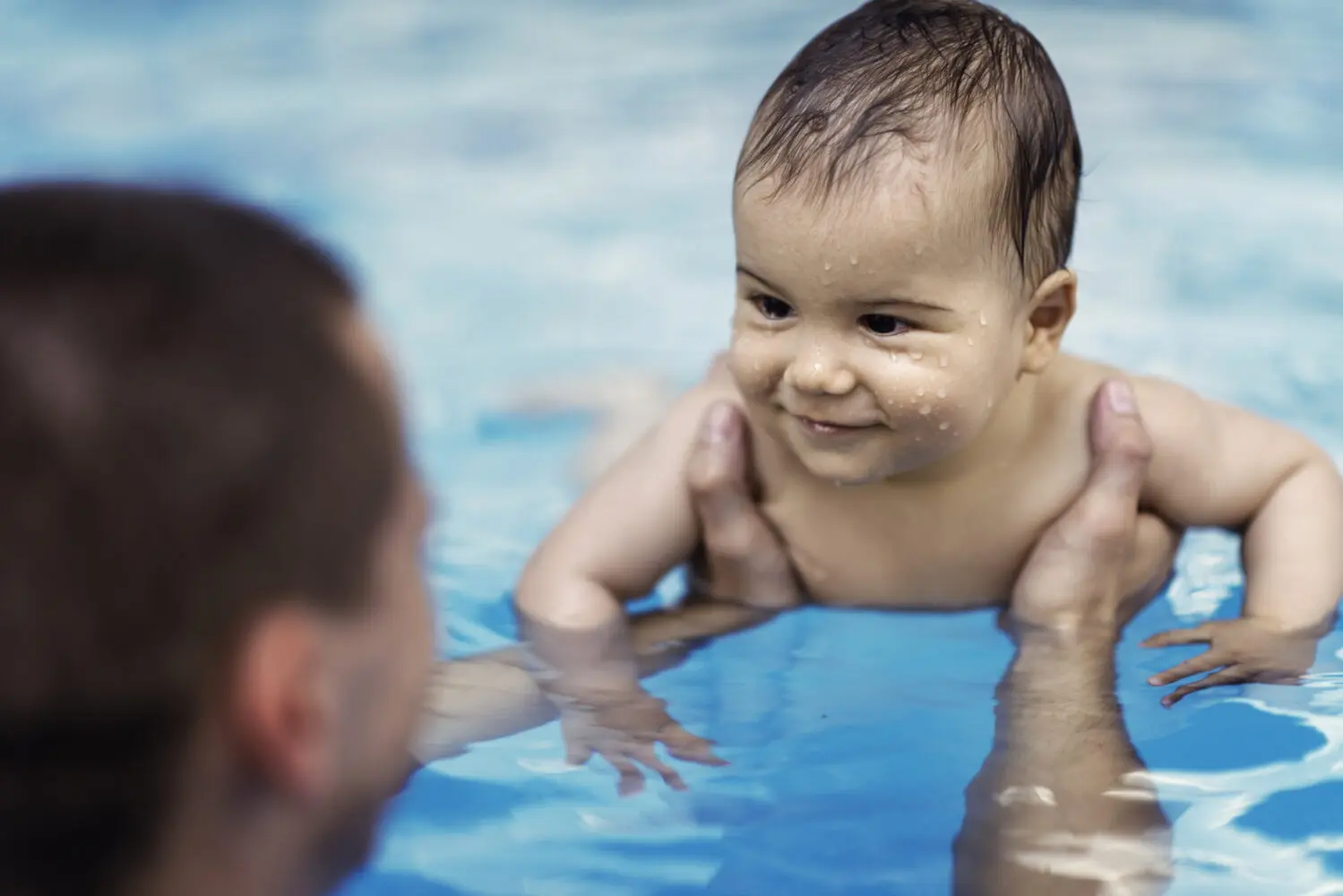 Child with adult in pool learning to swim